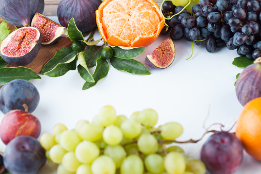 Empty white table with orange tangerine, figs and grape fruit . Healthy food background border with copy space