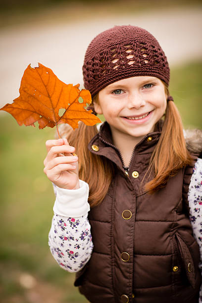 istock Little Girl Standing Outside on Fall Day and Holding Leaf 187483002
