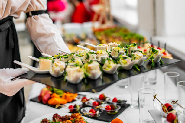 les mains d’une femme d’un serveur préparent de la nourriture pour une table de buffet dans un restaurant - Photo