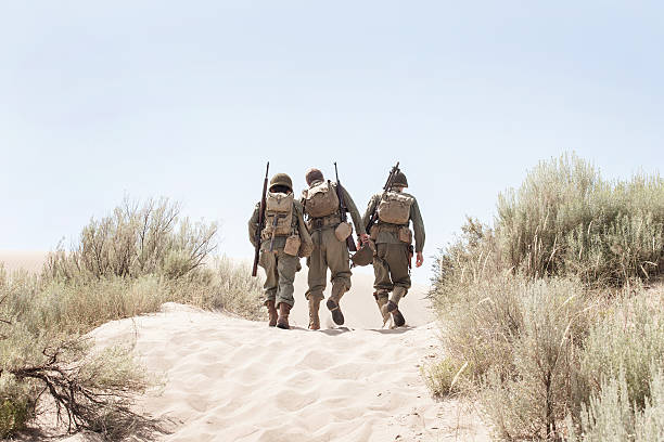 istock WWII soldiers trudging through white sand 187483457