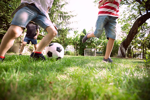 Happy family playing soccer in the backyard. Low angle view.