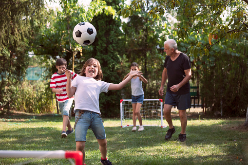 Happy family playing soccer in the backyard.