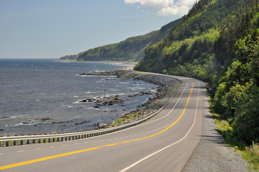 Highway 132 at the coast of Saint Lawrence River in Quebec, Canada. The route is part of the Gaspé Peninsula (Gaspésie), a northward continuation of the Appalachian Mountains called the Chic-Chocs.