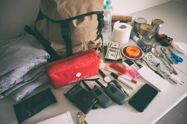 istock Emergency backpack equipment organized on the table. Documents, water,food, first aid kit and another items needed to survive. 1874869781