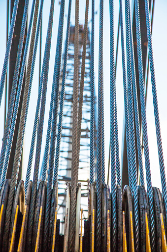 Stretched steel cables on the rollers of a cargo crane, close-up.