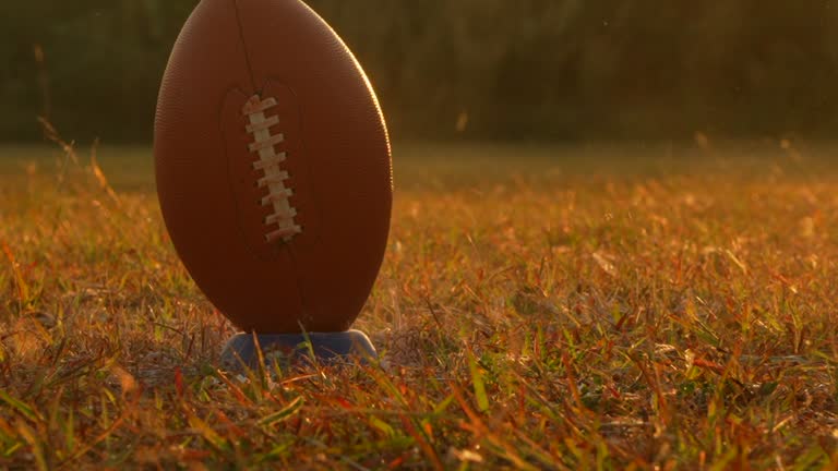 American football player with protective helmet and ball in sunset.