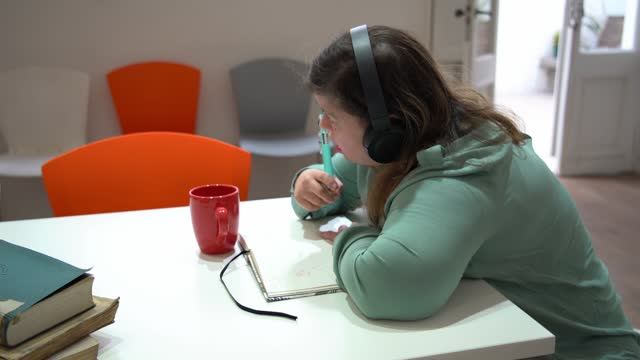 Mid adult woman with special needs listening music and studying in the classroom