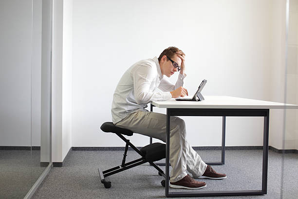 mann ist gebeugt tablet.bad sitzung haltung bei der arbeit - ergonomische tastatur stock-fotos und bilder