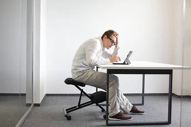 Photo of man is bent over  tablet.Bad sitting posture at work