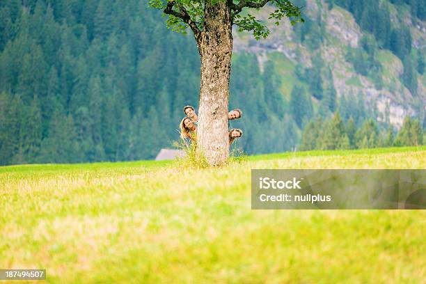 Famiglia Di Quattro Nascondersi Dietro Albero - Fotografie stock e altre immagini di Bambino - Bambino, Dietro, Famiglia con due figli