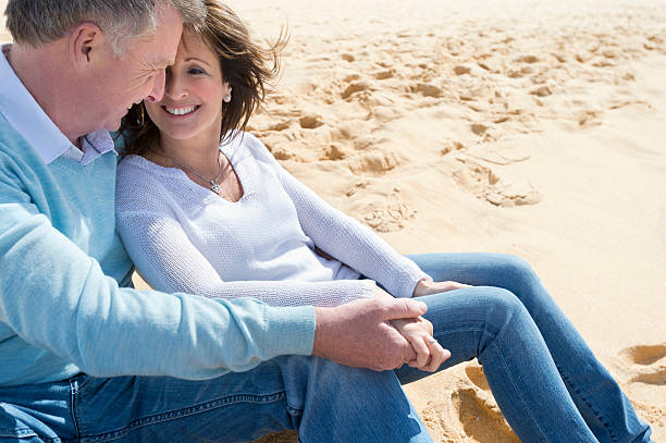 istock Happy mature couple sitting on the beach 187494889