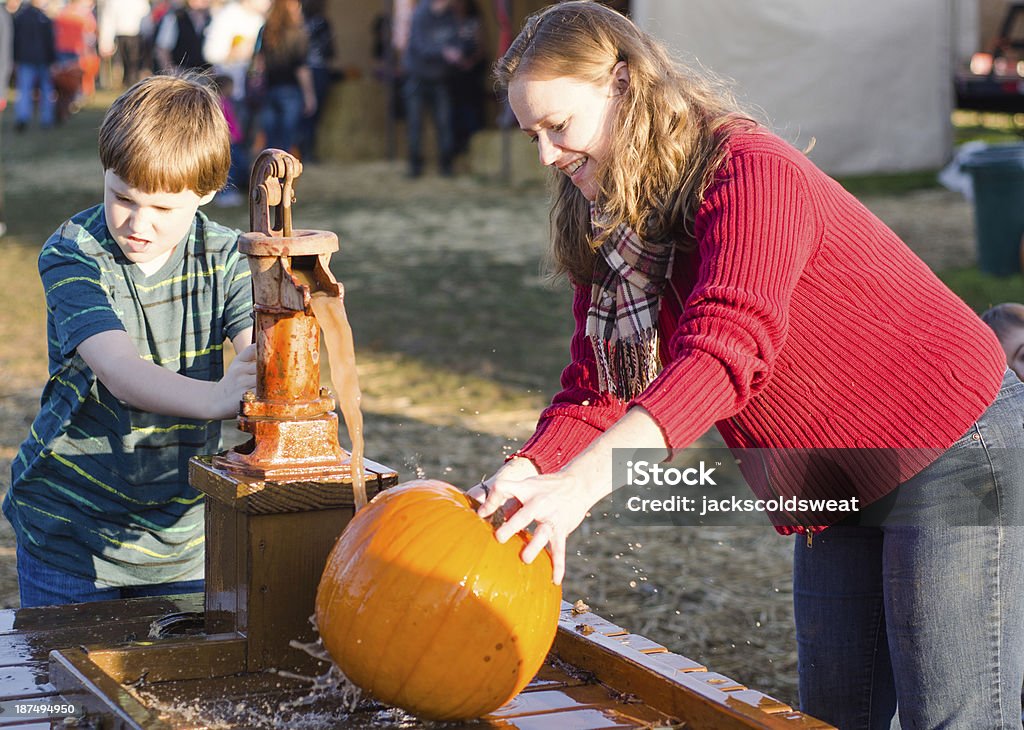 Young boy y madre limpieza pumpkins en una parcela de calabaza - Foto de stock de 30-39 años libre de derechos