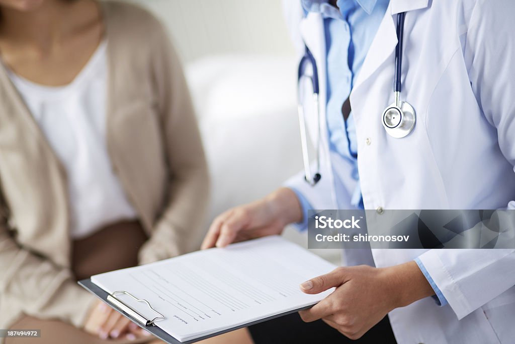 Doctor with medical card Female doctor holding application form while consulting patient Doctor Stock Photo