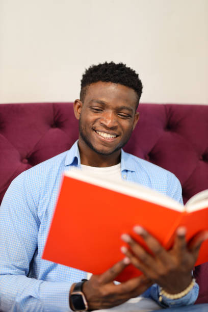 istock A happy and content young man immersed in the joy of reading and learning, surrounded by books. 1874951663