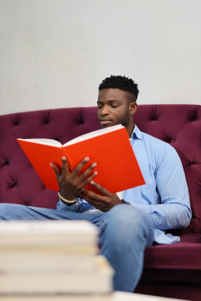 istock A studious adult in a modern library, deeply engaged in education, reading, and utilizing technology for research and learning. 1874951666