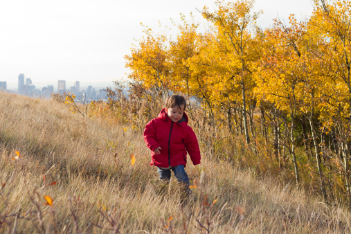 A little boy outside in autumn in a natural area with the city in the background.