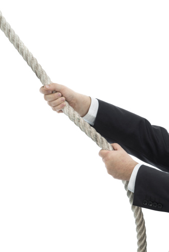 Caucasian businessman climbing up rope
