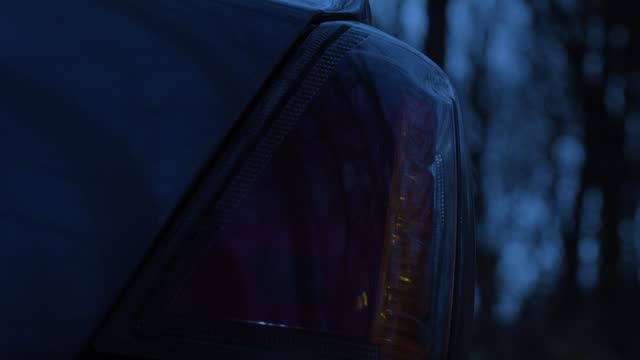 Close up sedan car flashing hazard warning lights abandoned at night on remote road