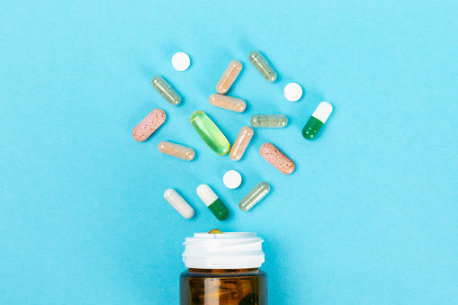 Vitamins and supplements. Variety of vitamin tablets in a jar on a texture background.Multivitamins with fresh and healthy fruits.Food supplements. Flat lay. Space for text.Copy space