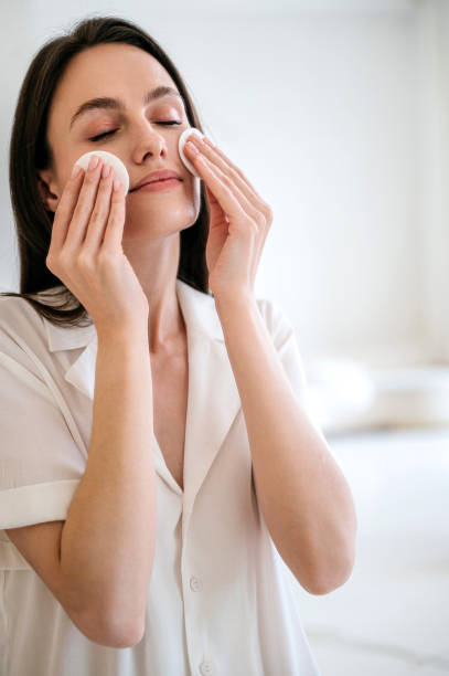 istock young female remove makeup using cotton sponge, standing in bathroom 1875023515