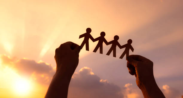 Teamwork and relations concept. woman holding human paper chains at sunrise. People are connected. Concept of human role. teamwork, family home, society, social network, and people concepto de trabajo en equipo y relaciones. mujer sosteniendo cadenas de papel humanas al amanecer. las personas están conectadas. concepto de rol humano. el trabajo en equipo, el hogar familiar, la sociedad, la red social y las personas