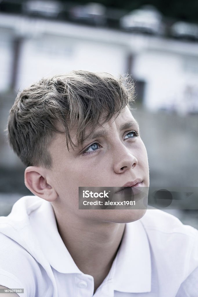 Sitting alone Teenage boy sitting alone on a gray background. 14-15 Years Stock Photo