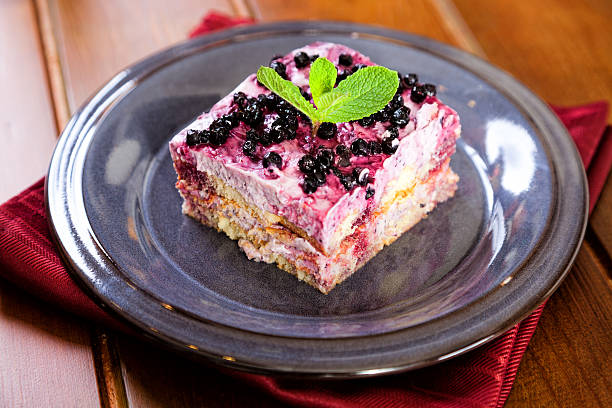 Fresh healthy multilayered dessert trifle with raspberries and blackberries on pastel blue background. Organic sweet food with dairy and forest fruits - closeup photography.