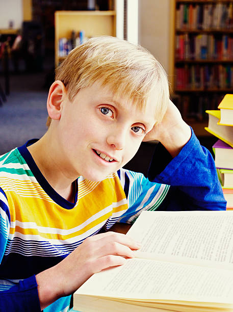 istock It's a great story! Smiling boy in library enjoying book 187509921