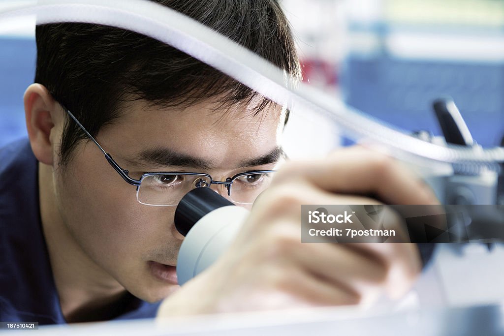 Primo piano di uomo occhio guardando attraverso il microscopio - Foto stock royalty-free di Ingegnere