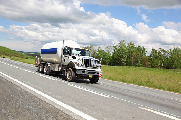 Large, white propane truck driving alone on highway road Propane truck delivering propane. Selective focus on truck. propane stock pictures, royalty-free photos & images