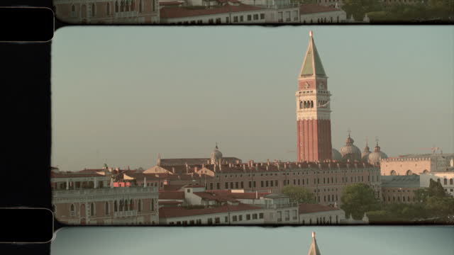 Old Film Aerial View of rooftops of Venice, Italy in sunshine, with St. Mark's Campanile and Basilica in the distance. 4K