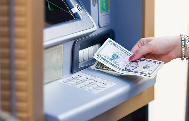 istock A female hand taking dollar bills out of an ATM 187511087