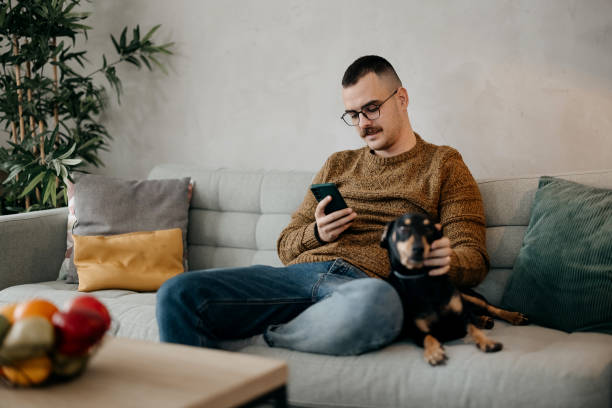 istock Man is using a mobile phone and petting his dog 1875123020