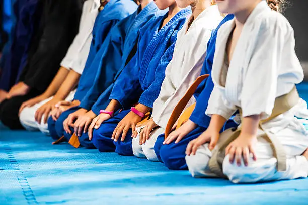 Unrecognizable group of children in a row on a karate training. Focus is on the middle.   