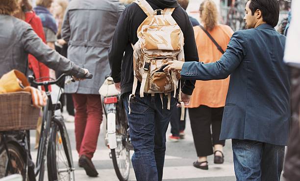 thief pulls wallet out of a man backpack - zakkenrollen stockfoto's en -beelden