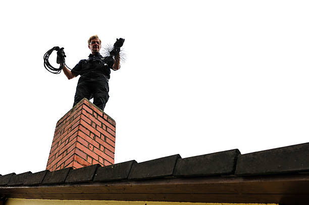 Look-up of cleaner cleaning brick chimney Chimney sweep is with his tool on the chimney to the fireplace to turn. sweeping photos stock pictures, royalty-free photos & images