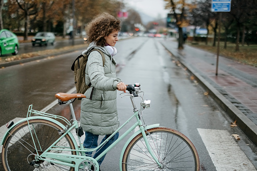 Woman pushes her bicycle on a rainy day