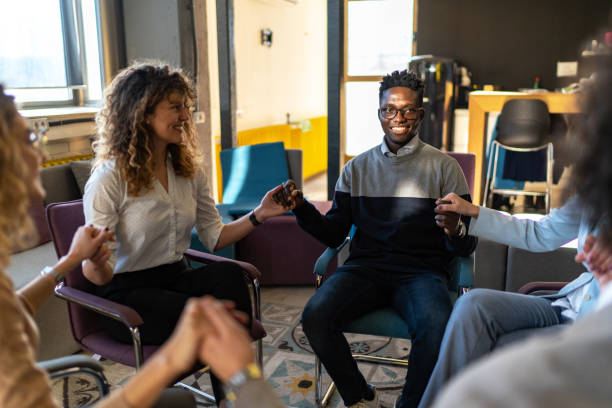 istock Multiracial group of people holding hands during a group therapy session 1875157280