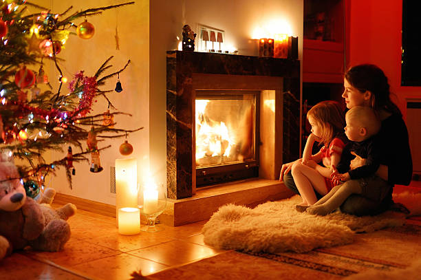 Young mother and her daughters by a fireplace stock photo