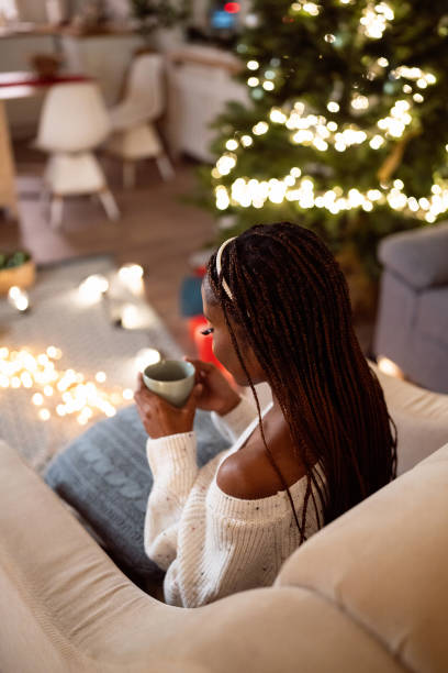 istock Woman Black ethnicity enjoying Christmas atmosphere, while drinking hot chocolate 1875173545