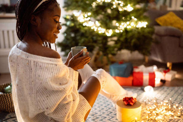 istock Woman Black ethnicity enjoying Christmas atmosphere, while drinking hot chocolate 1875173563