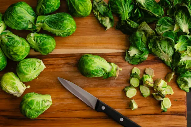 Peeled and trimmed baby cabbages with leaves and stems on a wood chopping board