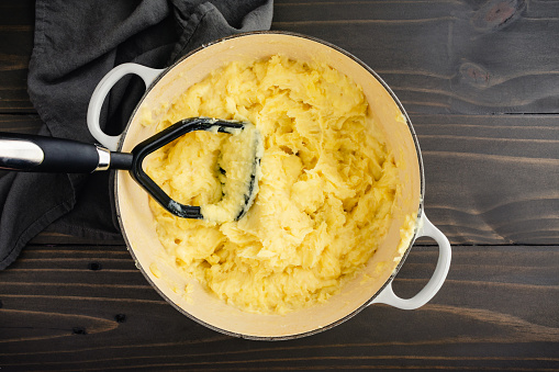 Mashing Yukon Gold potatoes with roasted garlic, mascarpone cheese, butter, and milk