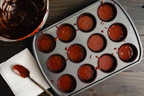 Unbaked chocolate cupcakes in a non-stick muffin tin with paper paper liners