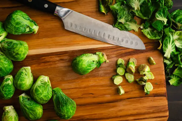 Peeled and trimmed baby cabbages with leaves and stems on a wood chopping board