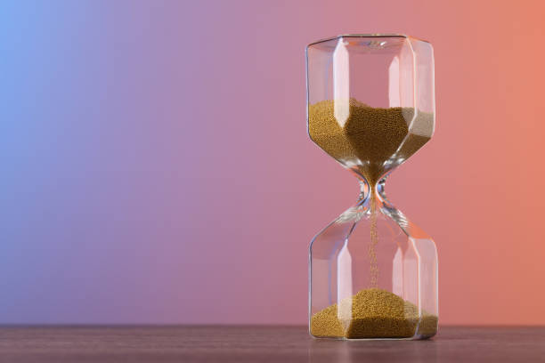 istock Hourglass with flowing sand on table against color background, space for text 1875190148