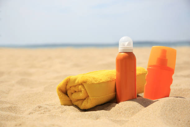 istock Sunscreens and rolled towel on sandy beach, space for text. Sun protection care 1875191723