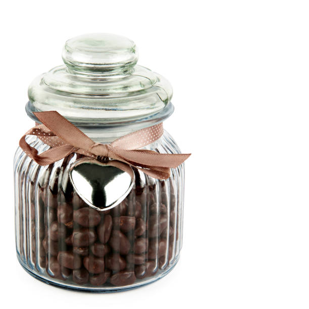 istock Chocolate dragee in a transparent glass jar isolated on a white. Free space for text. 1875194008