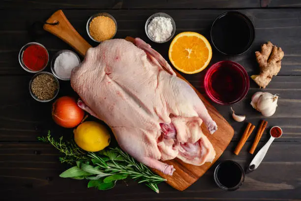 Whole duck, fresh herbs, and other ingredients for roasting a glazed whole duck