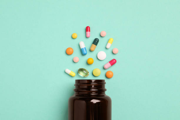 istock Plastic medical bottle with many different pills on turquoise background, flat lay 1875200707